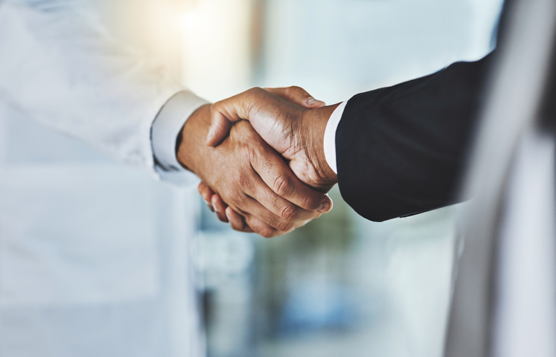 A doctor and a business person shake hands.