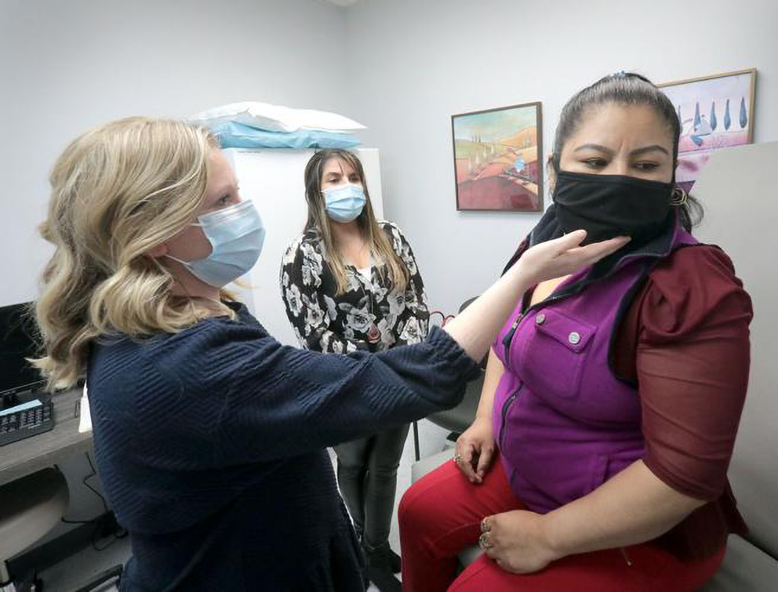 Dr. Beth Lake, a neurologist who volunteers at Specialty Care Free Clinic, examines patient Aquilina Cruz, with assistance from interpreter Alejandra Sochan. The clinic, which moved this year to Madison's South Side from a smaller space in Middleton, provides free specialty medical care to people without insurance.