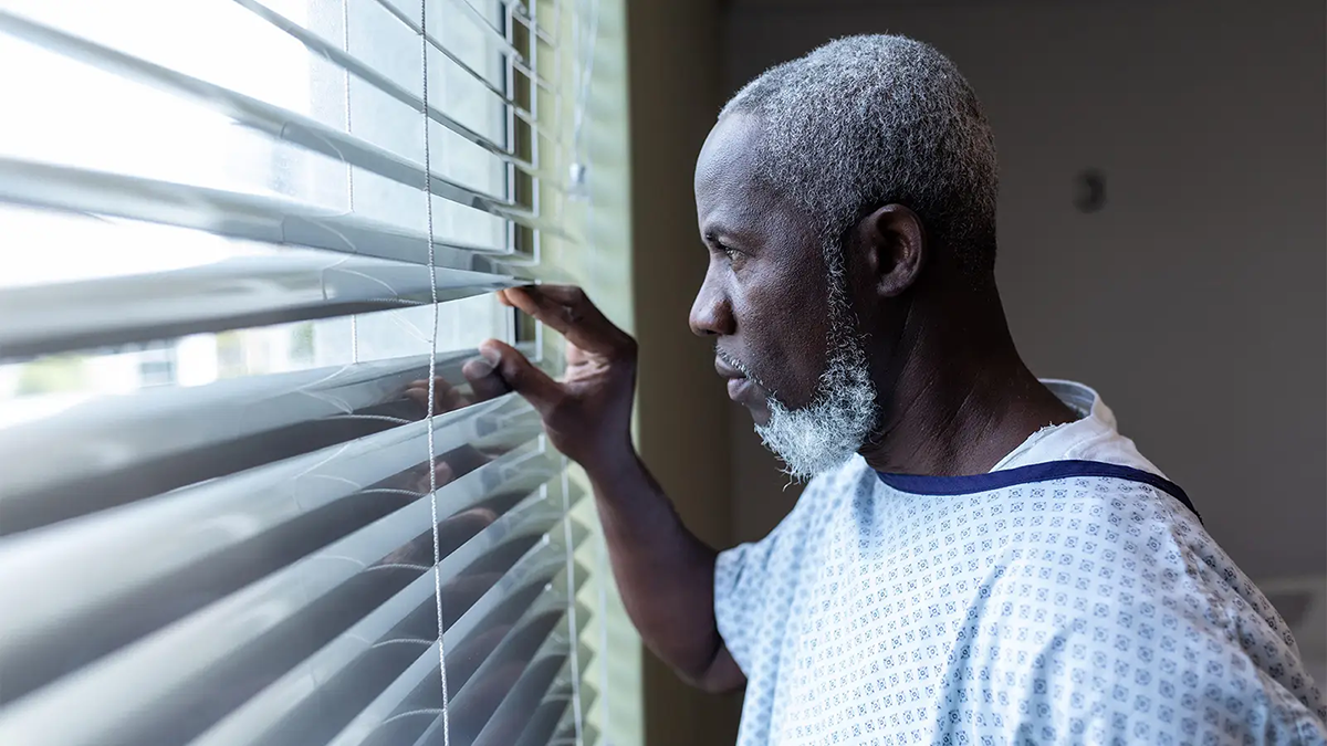 Black male patient looks out a clinic window.