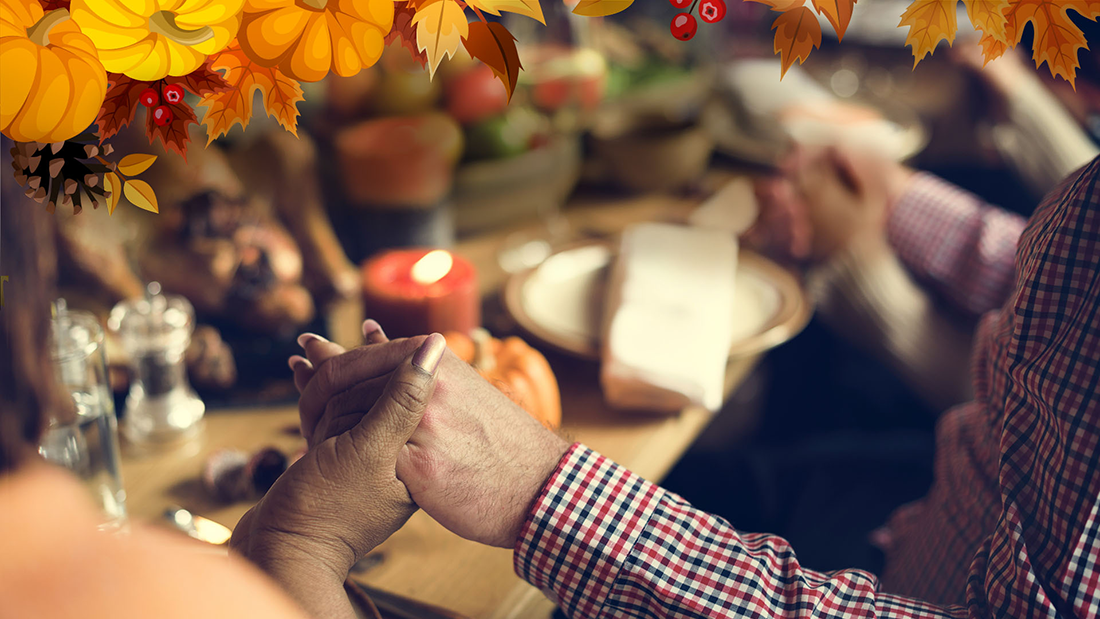 Family clasping hands around a Thanksgiving table.