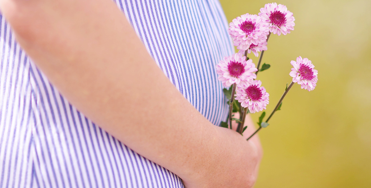 Pregnant person holding flowers.
