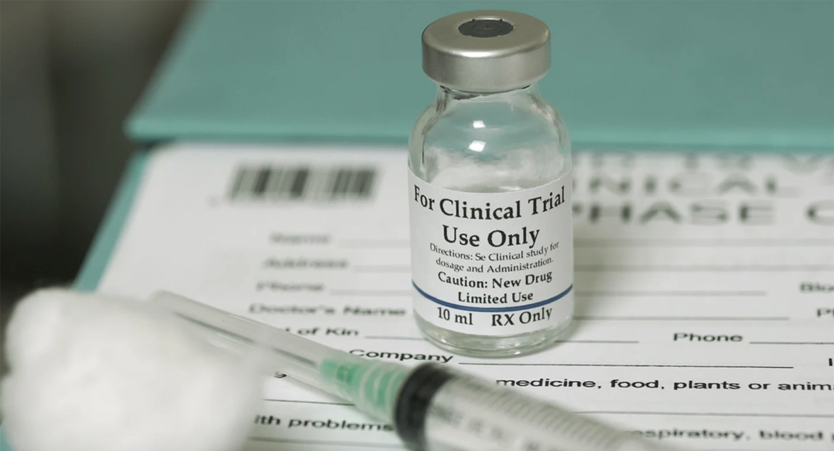 A vaccine vial that says "For clinical trial use only" and a syringe.