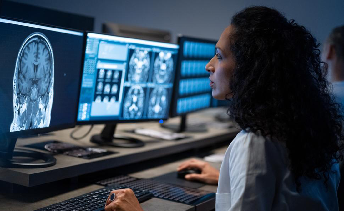 A researcher looks at an MRI scan of a human brain on a computer screen.
