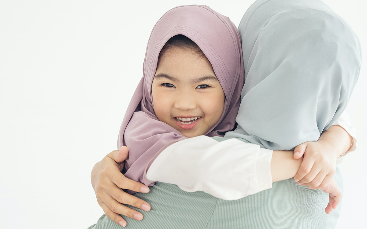 A mother and daughter hug while wearing hijabs.