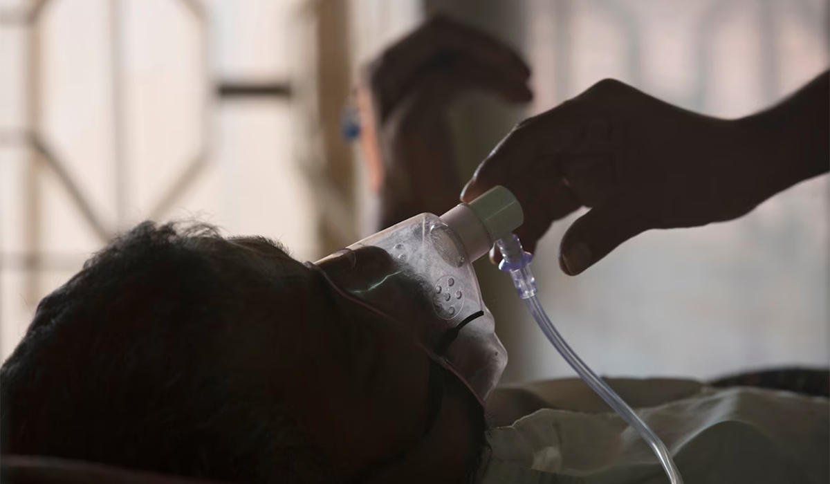 A caregiver adjusts the oxygen mask of a tuberculosis patient.
