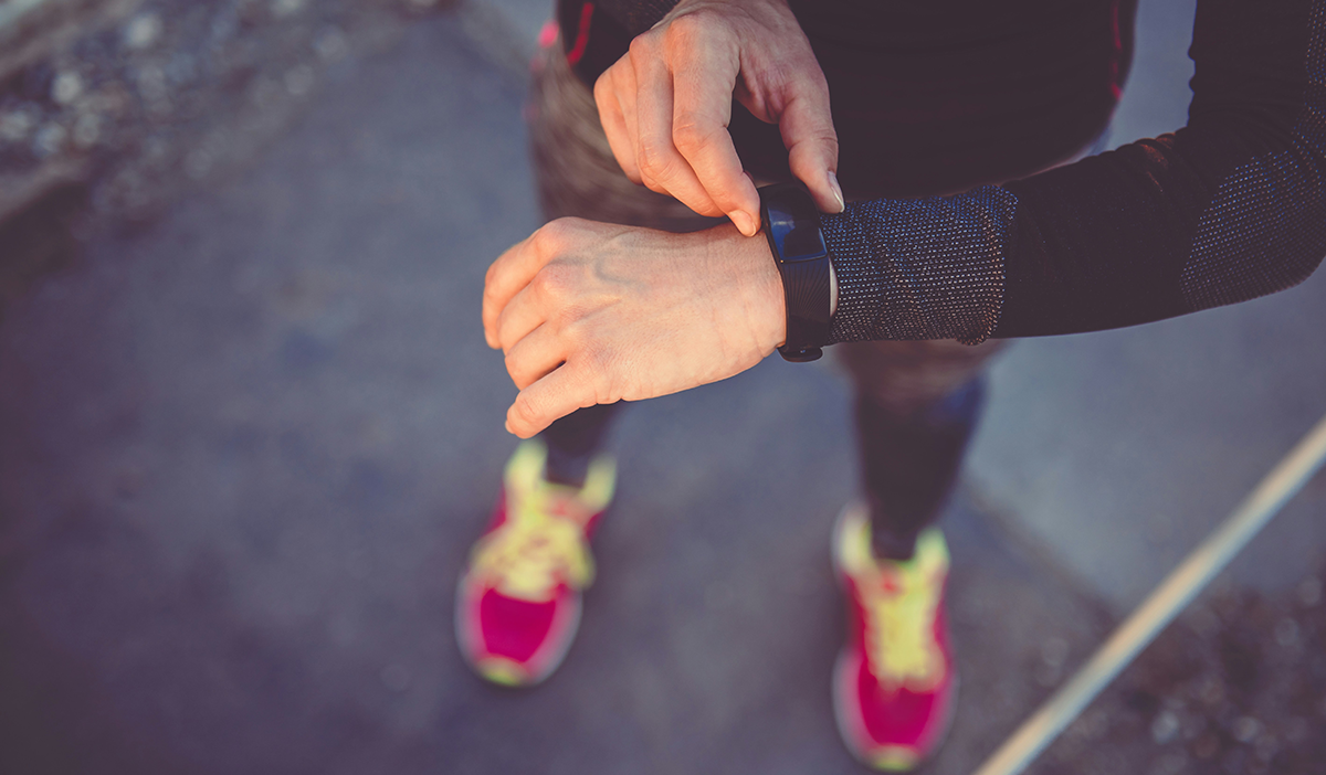 Person checking the fitness tracker device on their wrist.