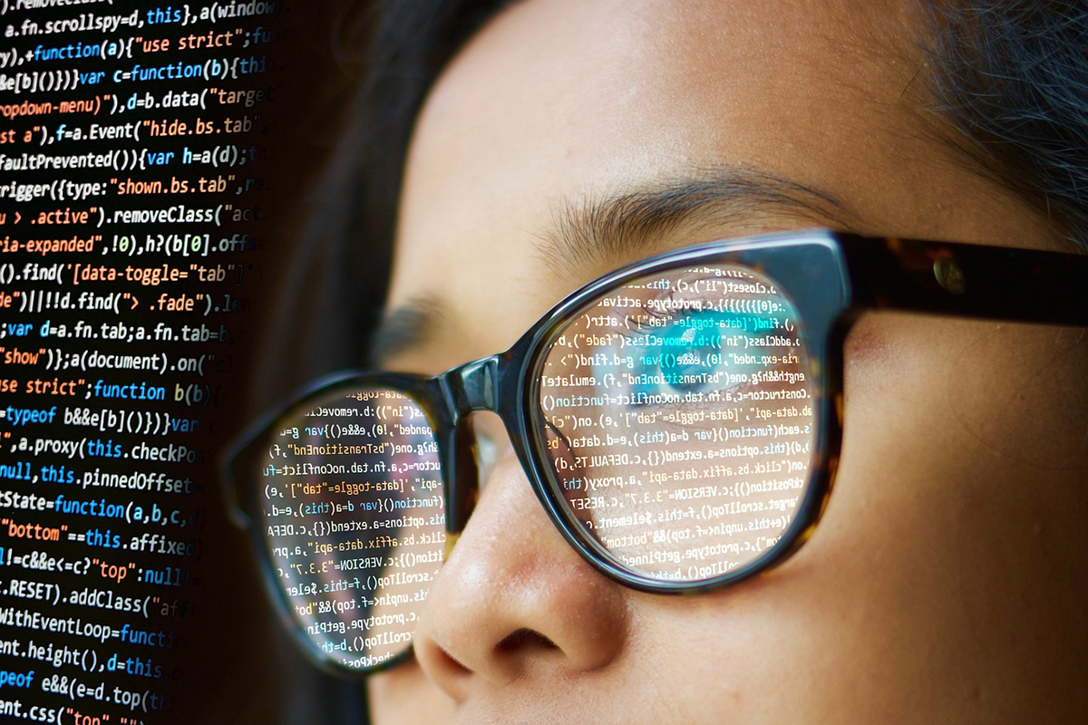 Computer code reflected in a person's eyeglasses.