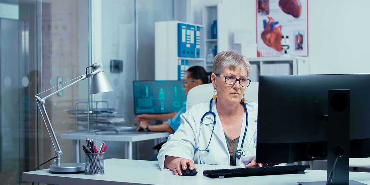 A healthcare professional works at a computer in a clinical setting.