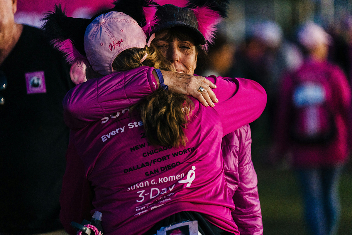 Two people in pink shirts embrace during a fitness event.